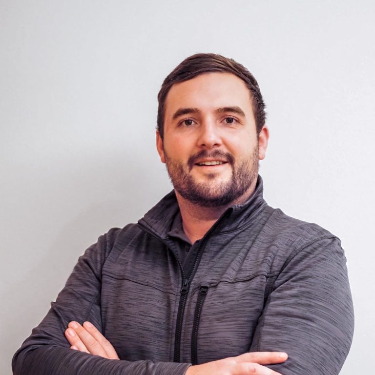 Mann mit kurzem Bart und dunklem Pullover, lächelt und steht mit verschränkten Armen. David Fuchs Inhaber Fuxx Elektrotechnik